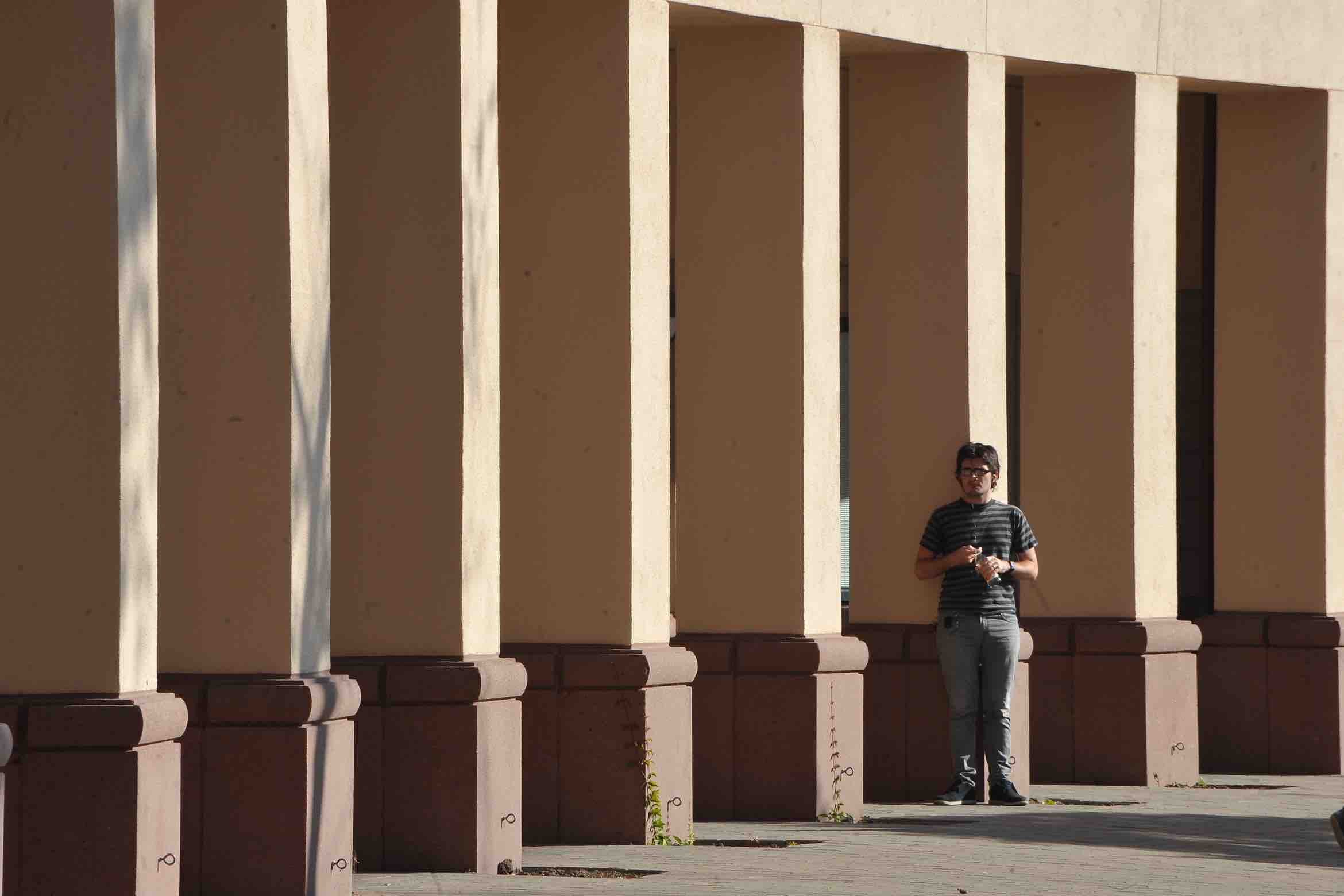 student standing in front of building columns