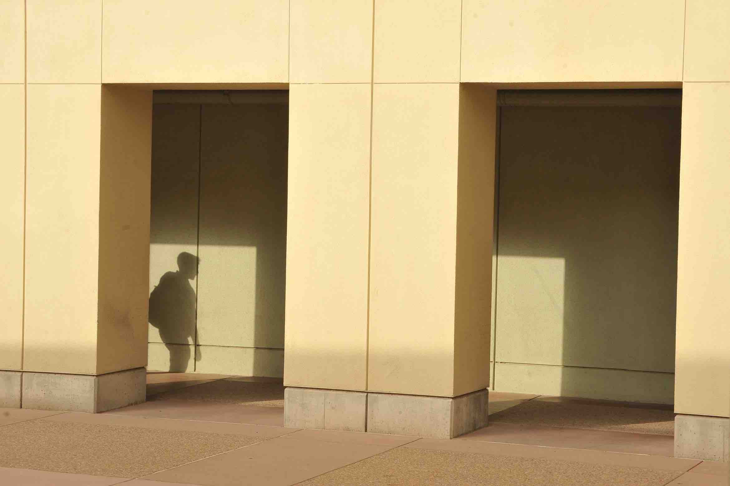 student's shadow behind building columns